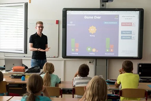 先生が電子黒板を使って授業をしている様子、子供たちは座り、真剣に聞いている