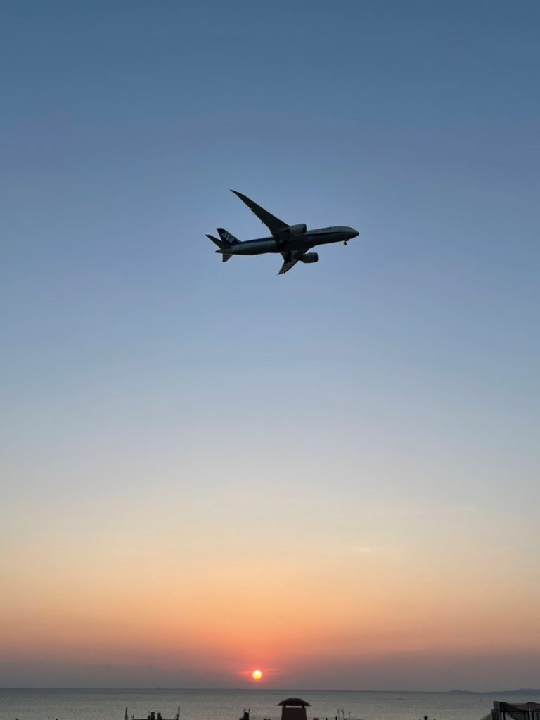 沖縄の海と空、空には飛行機が飛んでいる