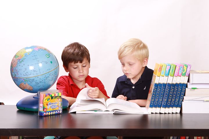 勉強をする子ども２人。
机には、本や地球儀、辞典など色んな勉強道具が置いてある。